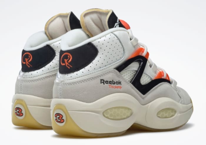 Back view of white, black, and orange Reebok shoes.